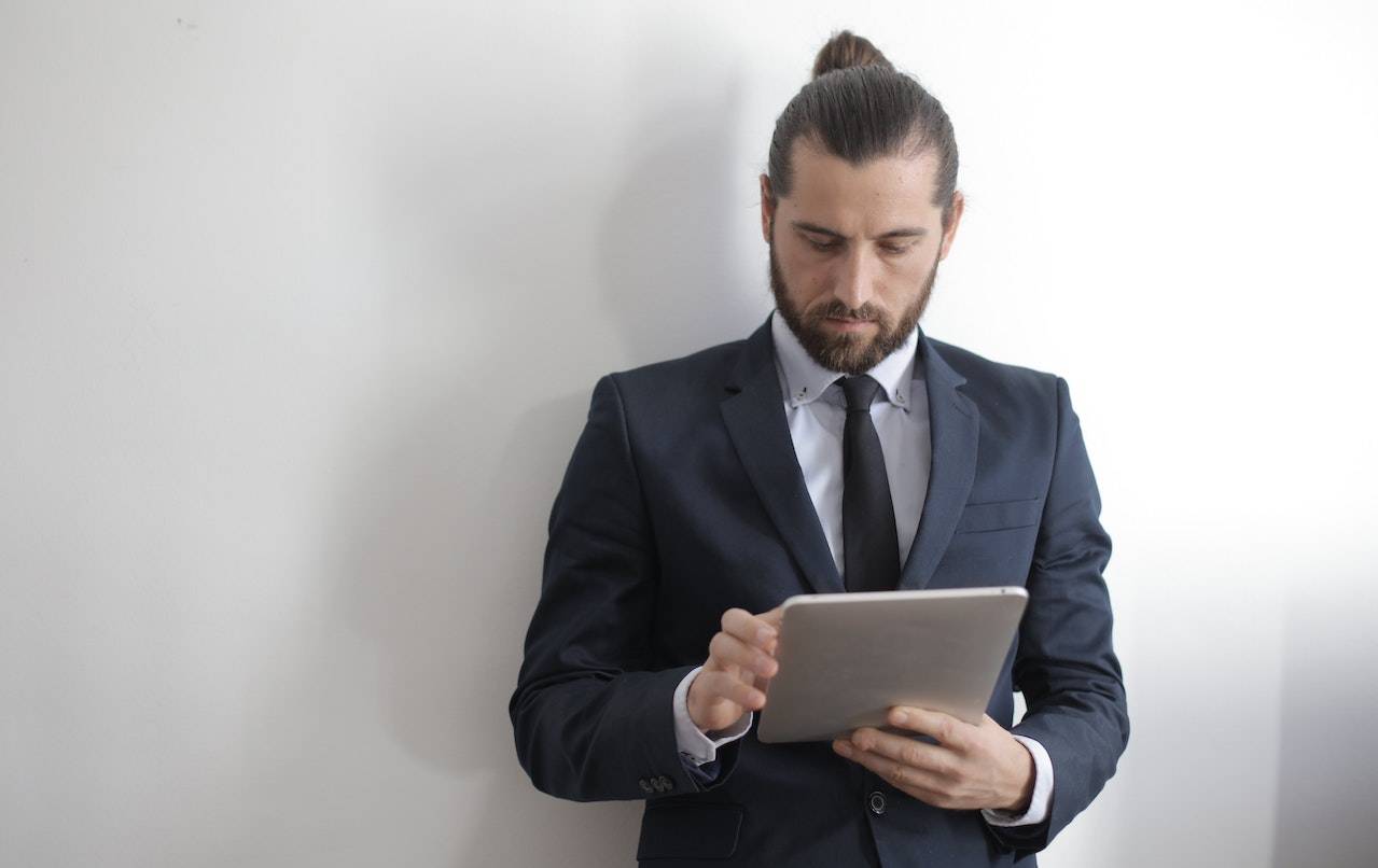 male employee in suit chats on ipad in between meetings