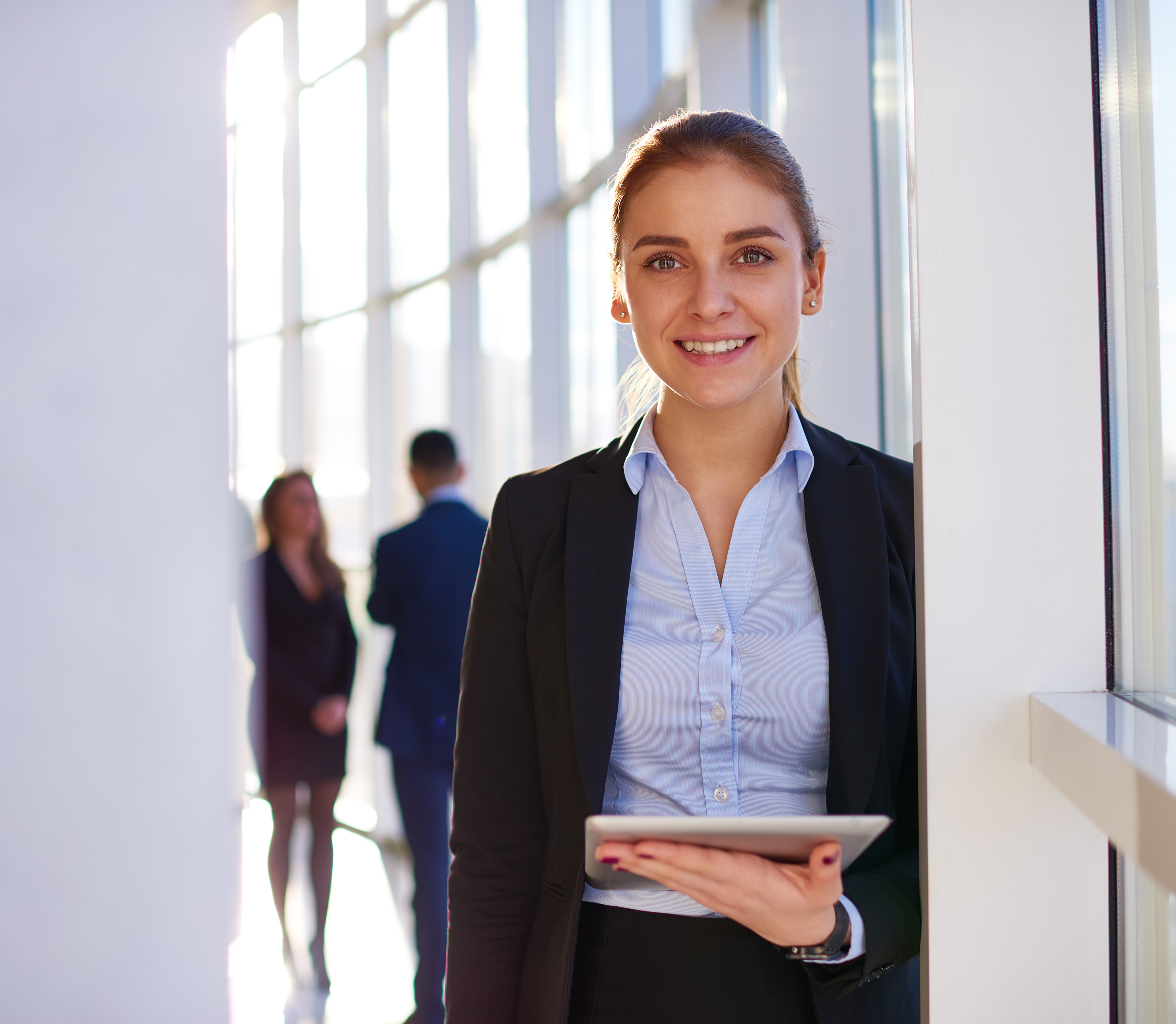 image of professional female at the office holding an ipad to represent the AI-powered transformation, revolutionizing internal communications and intranet efficiency, a LumApps hosted webinar with IABC on September 13, 2023