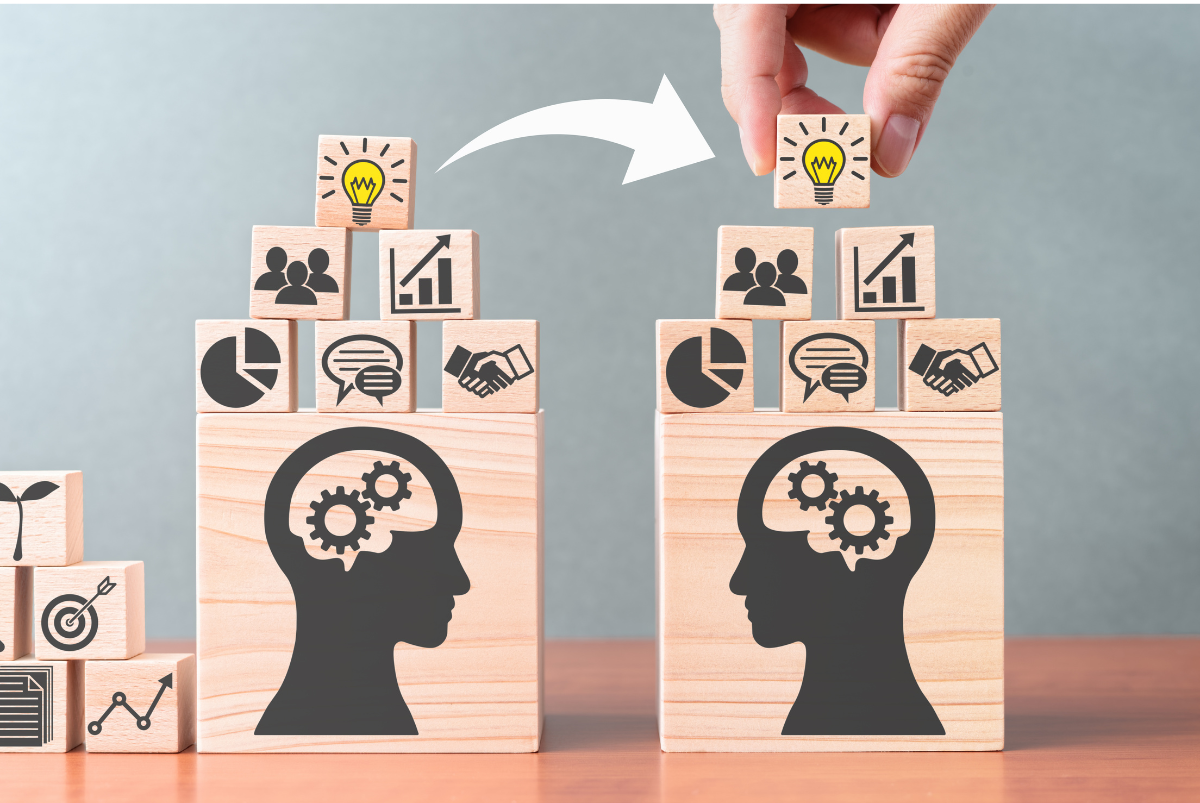 image of 2 wooden blocks stamped with images and icons - gears, lightbulbs, graphs, pie charts, hands shaking and conversation bubbles - to represent the key them for an upcoming IT and employee engagement webinar Improve Knowledge Sharing: The Key to Employee Productivity