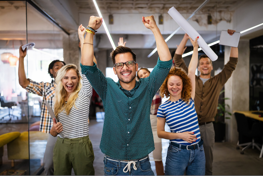 image of young professionals with fists in the air and smiling faces because they're happy and have a positive sentiment in their workplace